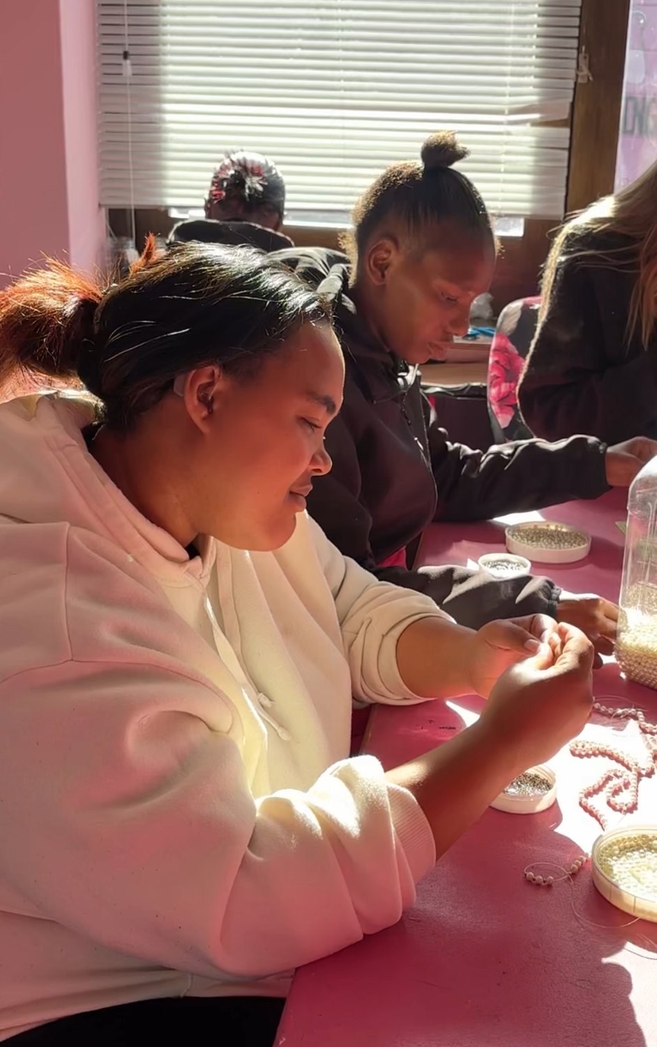 Meagan and Xoliswa from Wild Mongoo threading colourful beads by hand at the workshop table in George