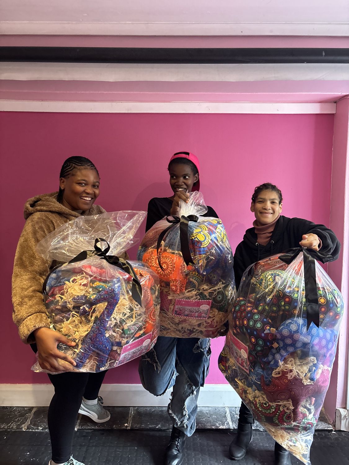 Rose, Sandisiwe and Chante from Wild Mongoo holding beautifully wrapped handmade gift hampers made in George